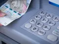 Dłoń z banknotem 500 zł przy bankomacie. Zastanawiasz się, przelew z mBanku do ING ile trwa?