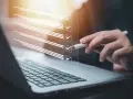 Ręka z długopisem zaznacza punkty na liście kontrolnej na ekranie laptopa. Proces ten może pomóc w ustaleniu, jak zmienić regulamin zakładowego funduszu świadczeń socjalnych.