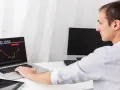 Mężczyzna analizuje wykres cen ropy i gazu na laptopie.