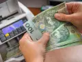Ręce trzymają banknoty 100 zł obok licznika pieniędzy. Czy przy wcześniejszej spłacie kredytu należy się zwrot odsetek?