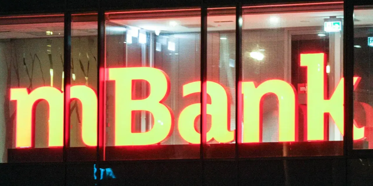 Jasne, oto propozycja tekstu alternatywnego:

Neonowy napis "mBank" świeci w nocy. To bank, do którego należą miliony Polaków, oferujący nowoczesne usługi finansowe.