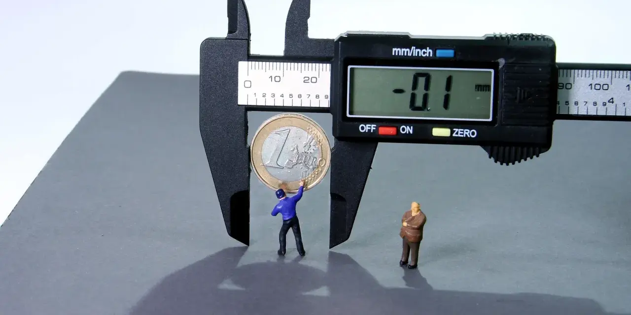 Figurki ludzi mierzą monetę suwmiarką, symbolizując, jak obliczyć odsetki od pożyczki.