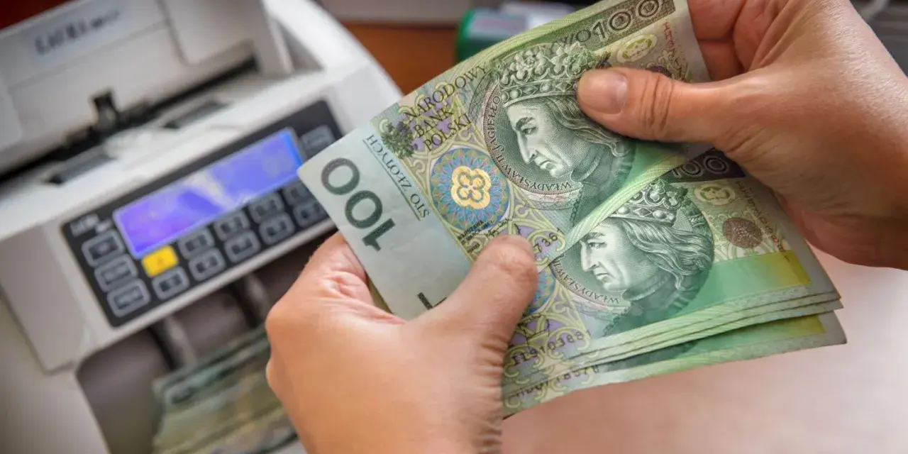 Ręce trzymają banknoty 100 zł obok licznika pieniędzy. Czy przy wcześniejszej spłacie kredytu należy się zwrot odsetek?