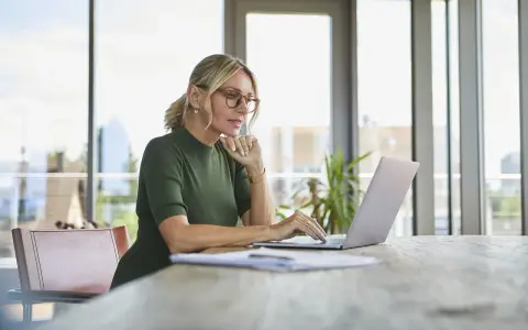 Kobieta w okularach pracuje na laptopie, szukając informacji, jak założyć konto w BIK.