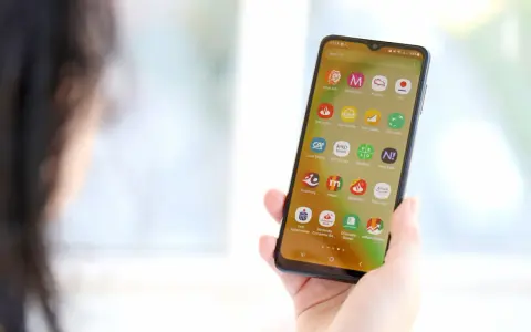 Dłoń trzyma smartfon z ikonami aplikacji bankowych. Widoczna ikona mBank, pomocna przy pytaniu jak zmienic numer telefonu mbank.