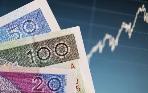 Polskie banknoty 20, 50, 100 zł na tle wykresu giełdowego. Bankowy fundusz gwarancyjny chroni depozyty do 100 tys. euro.