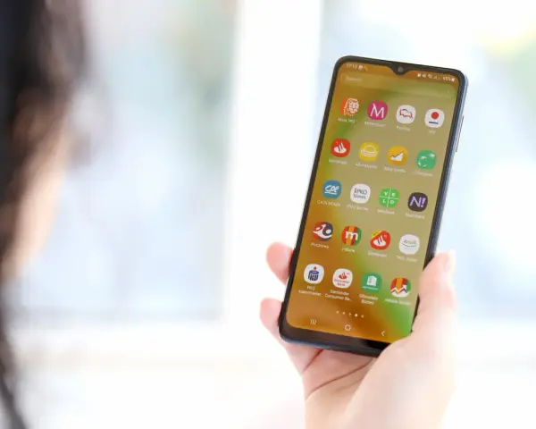 Dłoń trzyma smartfon z ikonami aplikacji bankowych. Widoczna ikona mBank, pomocna przy pytaniu jak zmienic numer telefonu mbank.