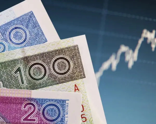 Polskie banknoty 20, 50, 100 zł na tle wykresu giełdowego. Bankowy fundusz gwarancyjny chroni depozyty do 100 tys. euro.