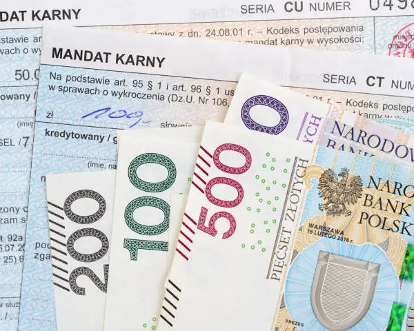 Mandaty karne i polskie banknoty 100, 200, 500 zł. Jak zapłacić mandat mBank? Dokumenty i pieniądze na stole.