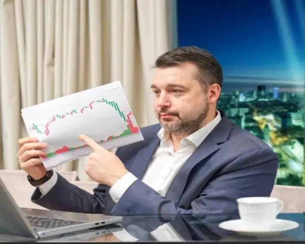 Mężczyzna w garniturze analizuje wykres giełdowy, zastanawiając się, jak zarobić na giełdzie 200 złoty dziennie.