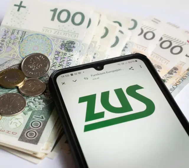 Złotówki i monety obok telefonu z logo ZUS. Pamiętaj o płaceniu składek, bo kto nie płaci funduszu pracy, ten ma problemy.