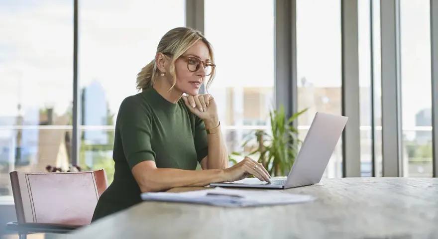 Kobieta w okularach pracuje na laptopie, szukając informacji, jak założyć konto w BIK.