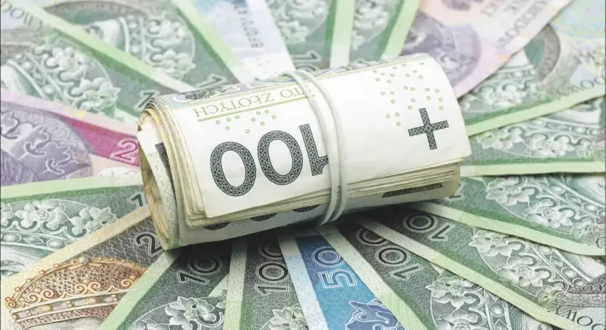 Zwijana paczka banknotów 100 zł na tle innych polskich banknotów. Ilustruje, jakim gwarancjom podlegają ubezpieczeniowe fundusze kapitałowe.
