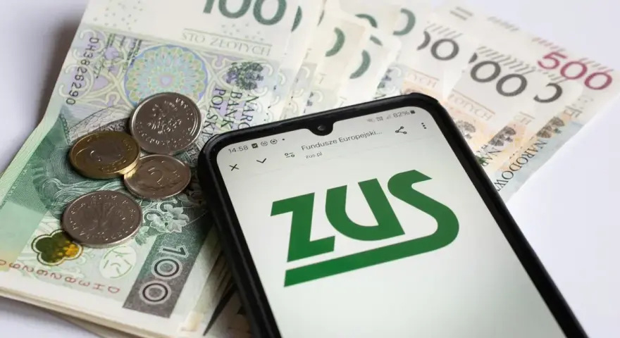 Złotówki i monety obok telefonu z logo ZUS. Pamiętaj o płaceniu składek, bo kto nie płaci funduszu pracy, ten ma problemy.