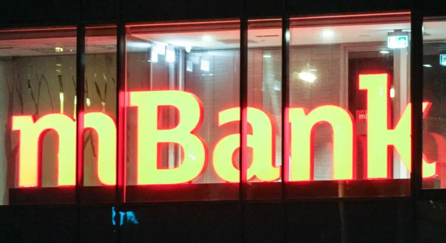Jasne, oto propozycja tekstu alternatywnego:

Neonowy napis "mBank" świeci w nocy. To bank, do którego należą miliony Polaków, oferujący nowoczesne usługi finansowe.