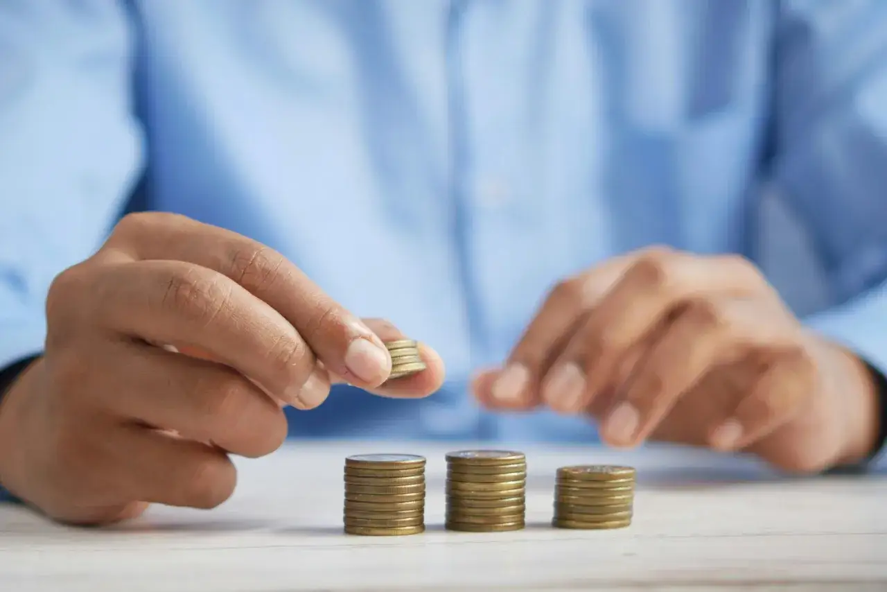 Ręka układa monety, symbolizując drogę do tego, jak się oddłużyć z chwilówek i odzyskać kontrolę nad finansami.