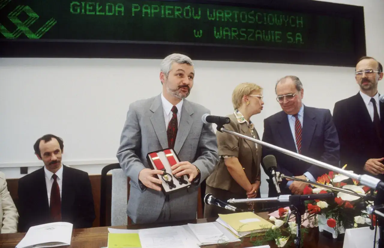 Mężczyzna prezentuje szelki na tle napisu