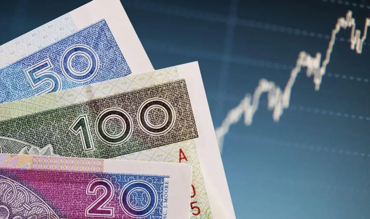 Polskie banknoty 50, 100, 200 zł na tle wykresu giełdowego. Dowiedz się, co to bankowy fundusz gwarancyjny.