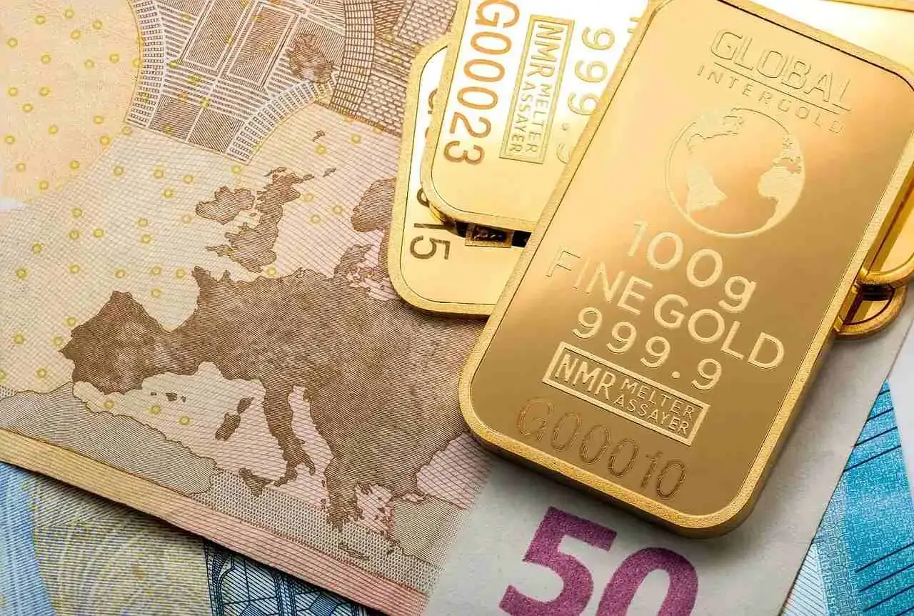 Sztabki złota inwestycyjnego na tle banknotów euro. Zastanawiasz się, gdzie kupić złoto inwestycyjne? Oto odpowiedź.